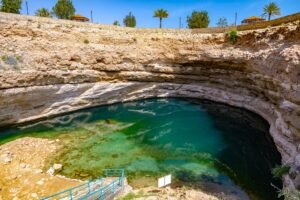 Blue-green water surrounded by limestone rock at Bimmah Sinkhole in Oman