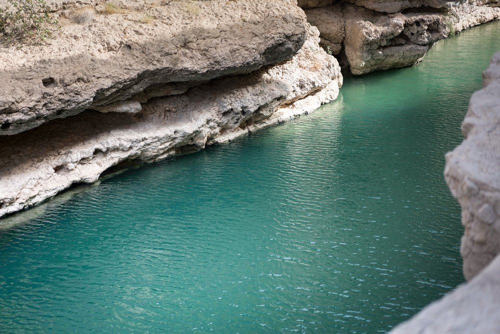 Turquoise water surrounded by rocky canyon walls at Wadi Shab in Oman
